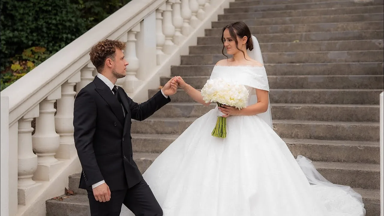Groom offering his hand to the bride on a white stone staircase