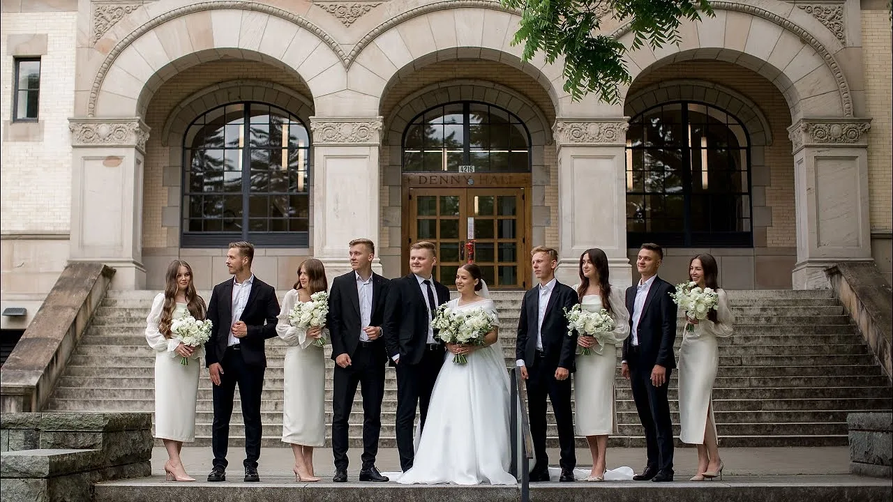Wedding party lined up on the steps of an arched stone entrance