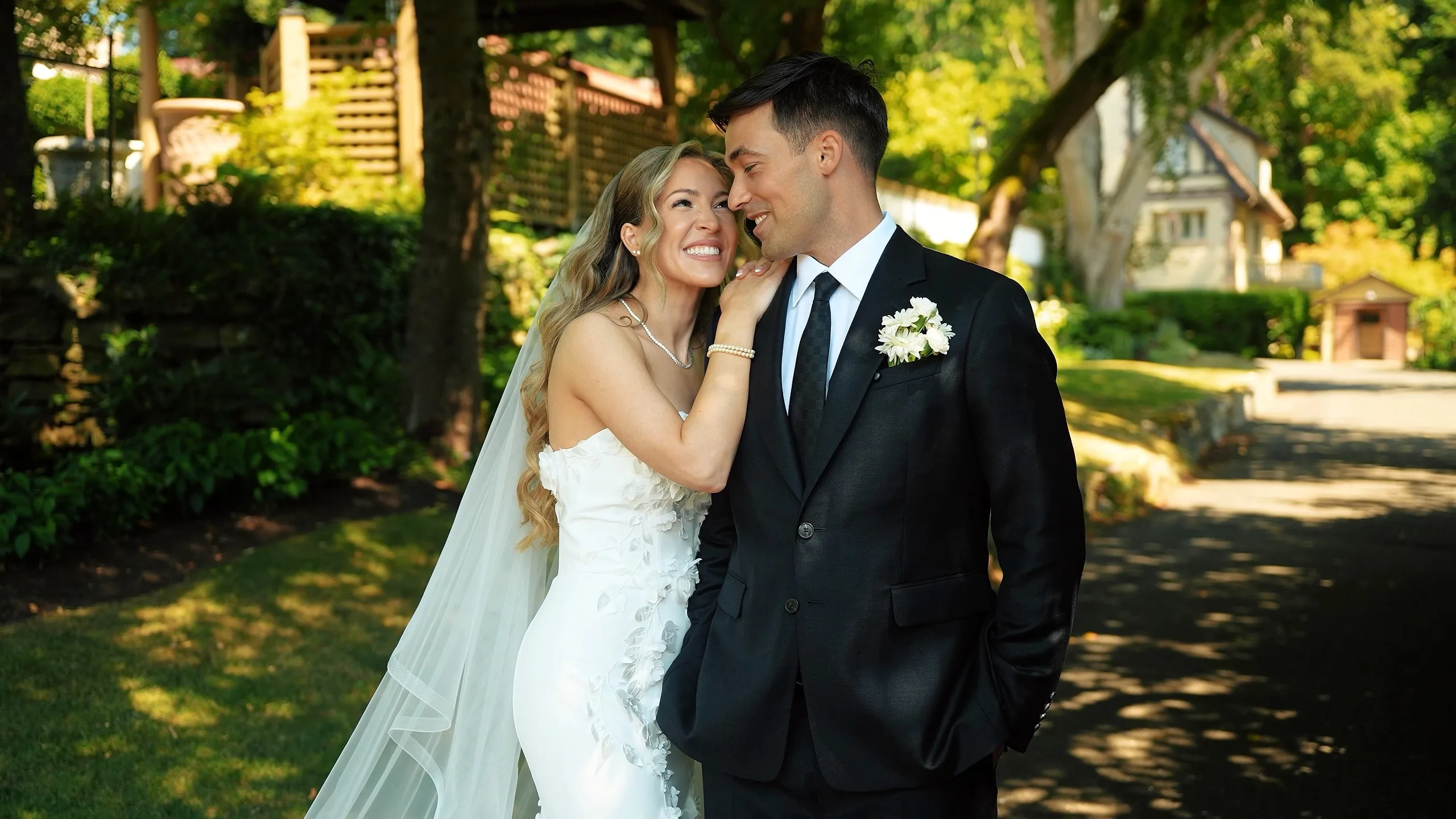 Bride and groom laughing cheek to cheek on a sunny garden path