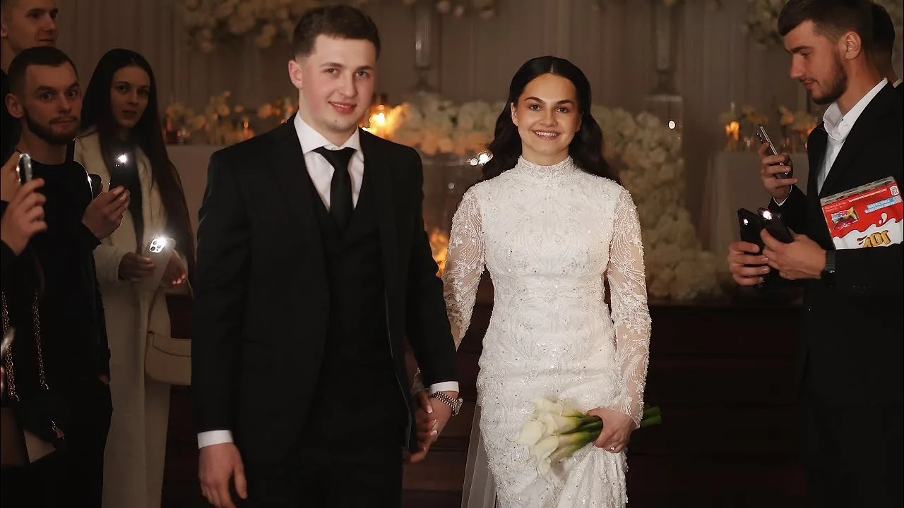 Bride and groom walking through guests holding phone lights