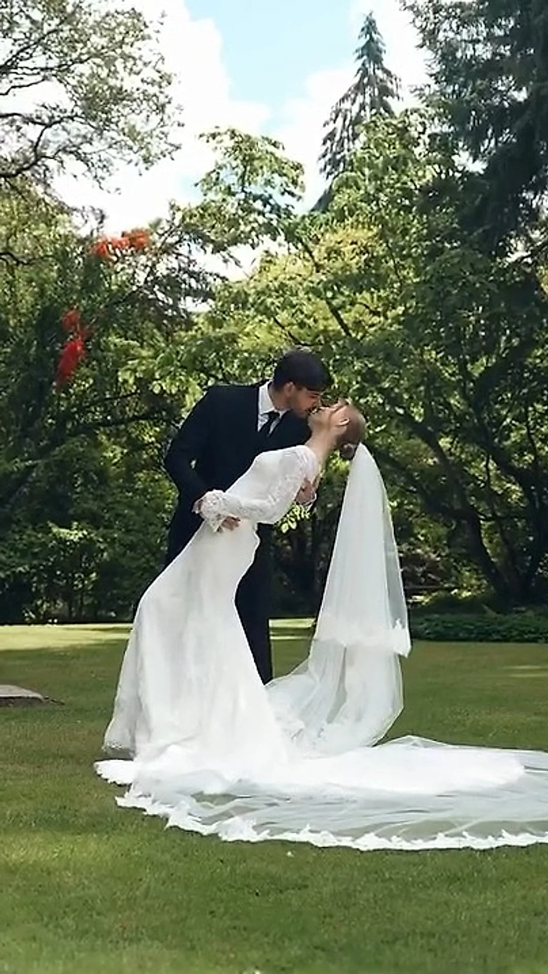 Groom dipping the bride for a kiss on a garden lawn